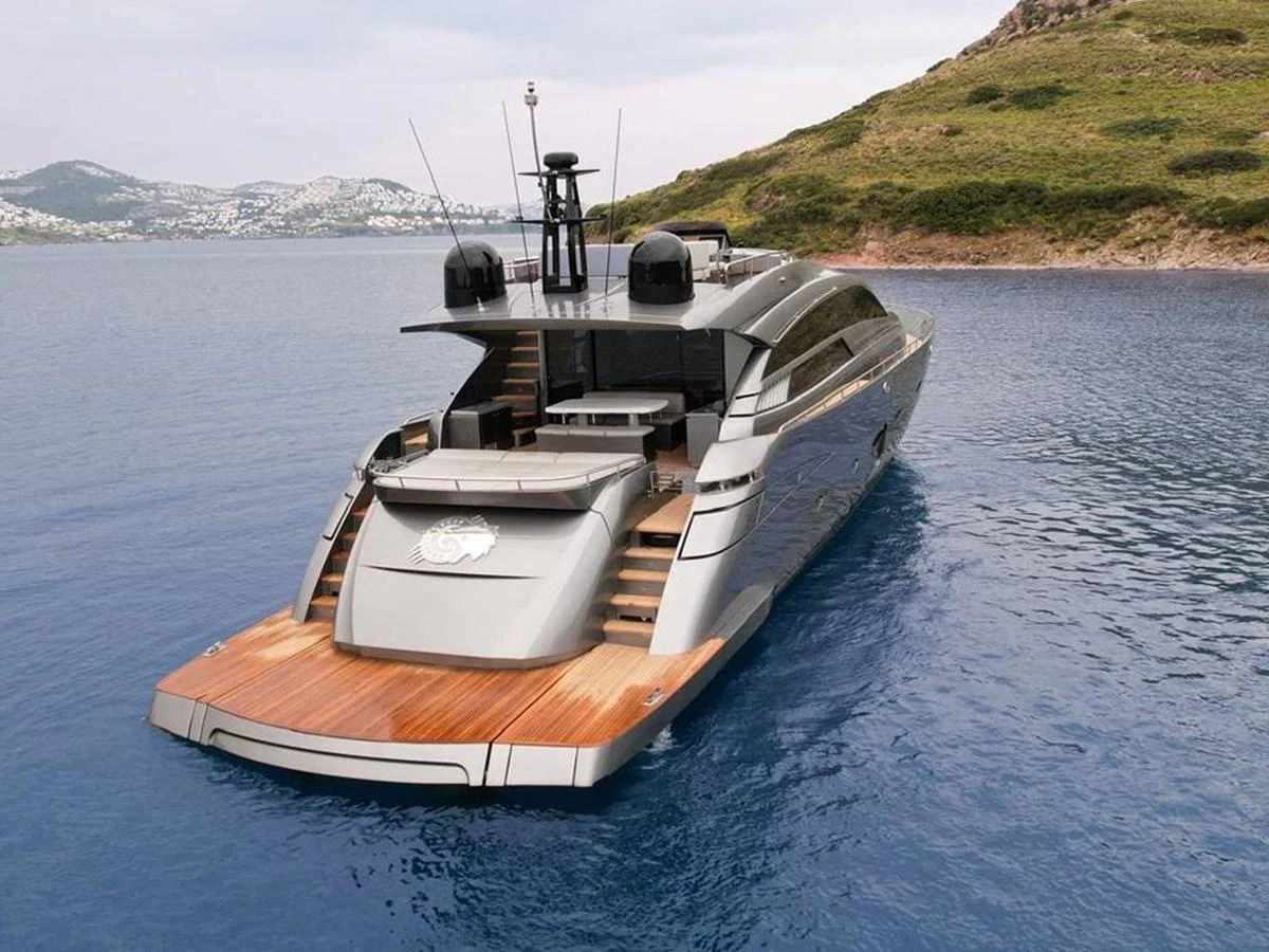 A sleek and modern yacht is anchored in calm waters near a picturesque coastline. aboard HONEY BADGER Yacht for Sale