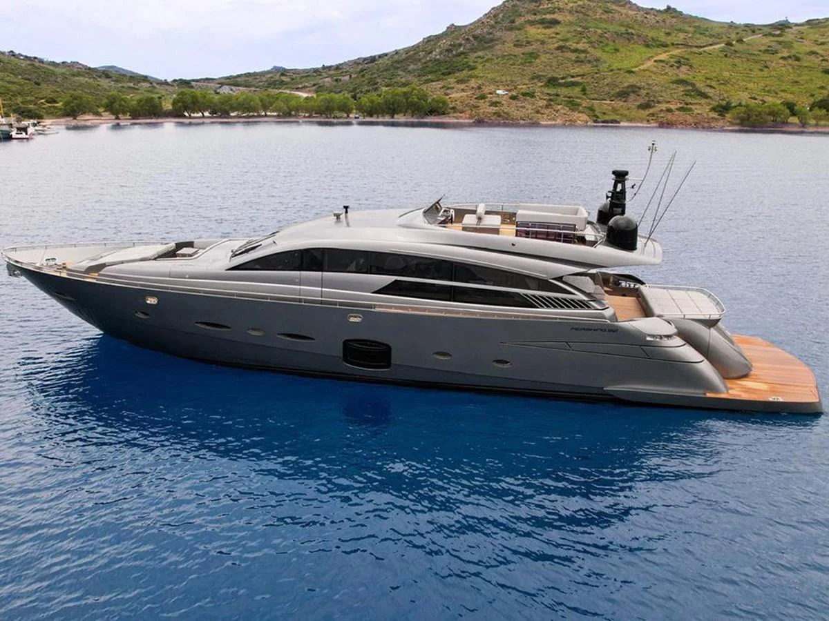 A sleek, modern yacht is anchored in a tranquil bay with scenic hills in the background. aboard HONEY BADGER Yacht for Sale