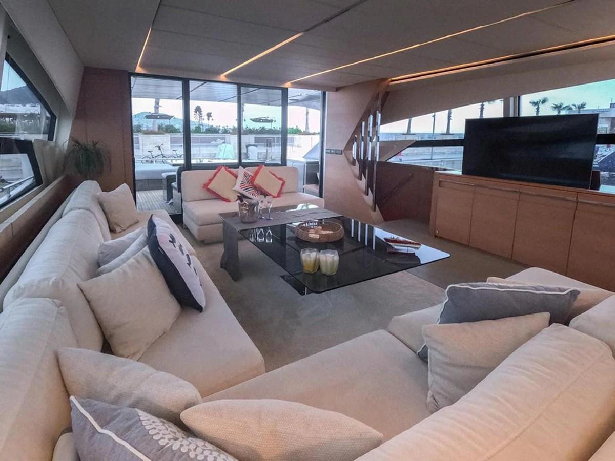 The salon features plush seating, a sleek coffee table, and large windows offering panoramic views. aboard HONEY BADGER Yacht for Sale