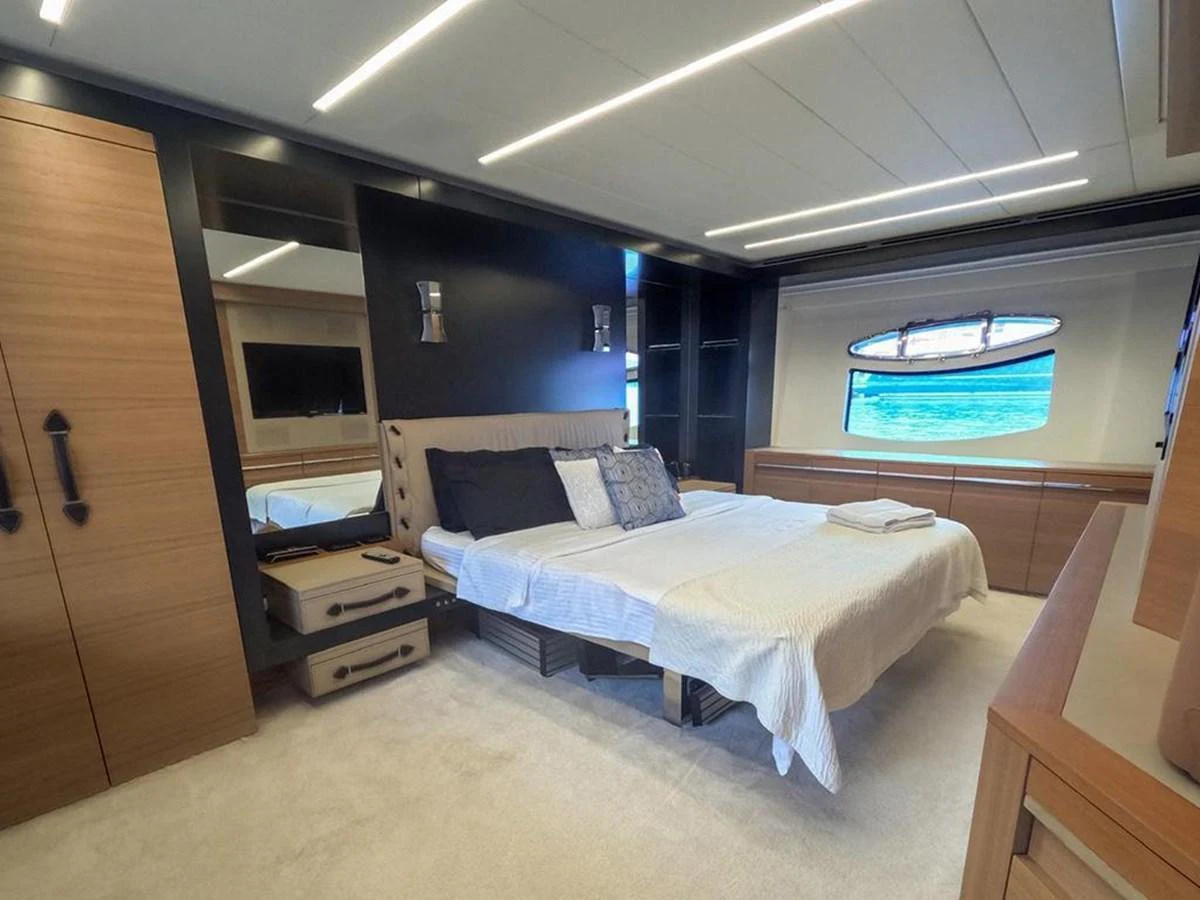 The stateroom features a luxurious bed with modern furnishings and ample natural light. aboard HONEY BADGER Yacht for Sale