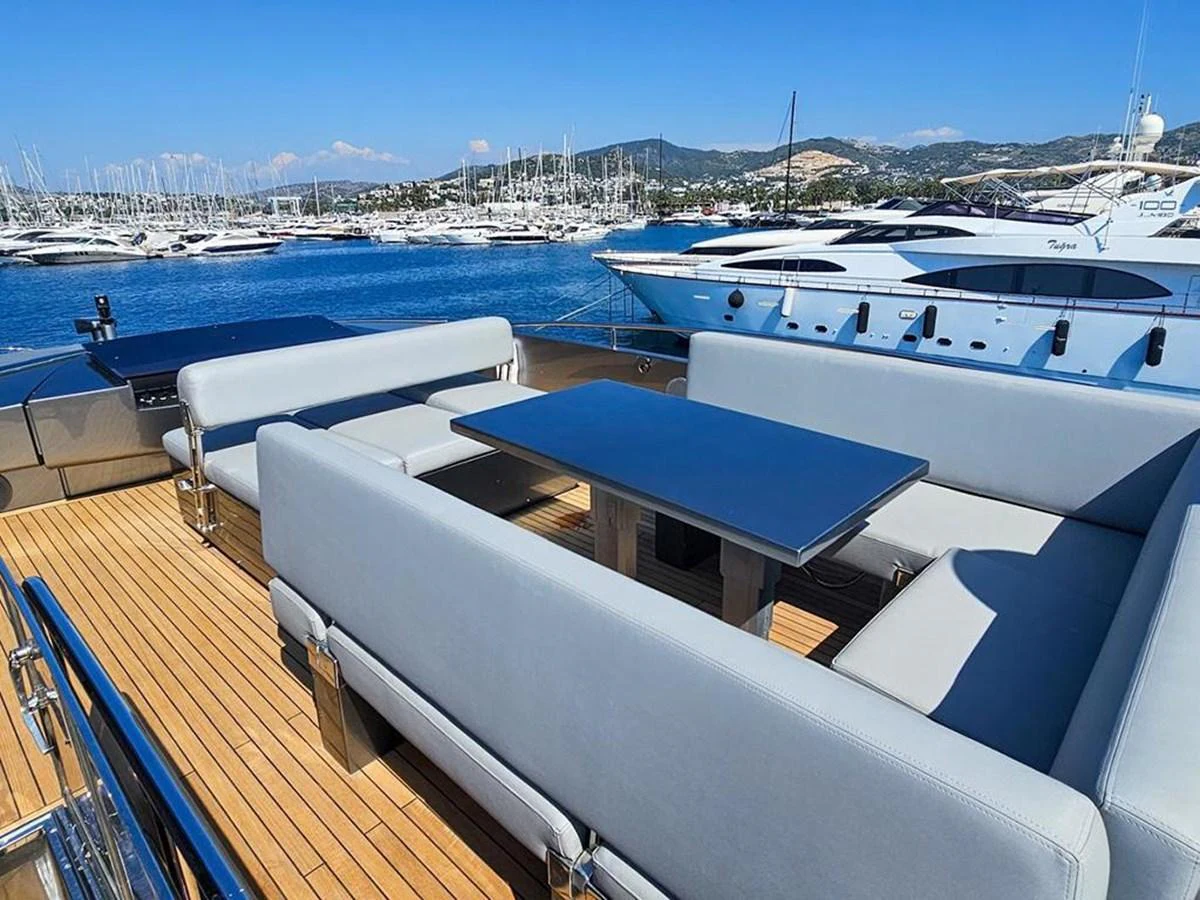 The aft deck features a spacious seating area with comfortable sofas and a dining table, perfect for alfresco dining with a view of the marina. aboard HONEY BADGER Yacht for Sale