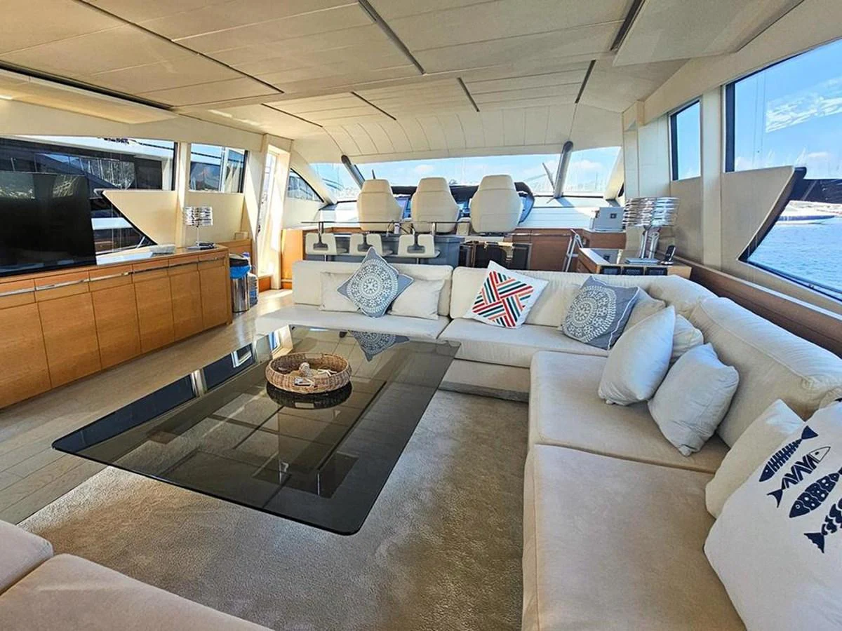 The salon features a spacious seating area with plush cushions and a sleek glass coffee table, offering panoramic views through large windows. aboard HONEY BADGER Yacht for Sale
