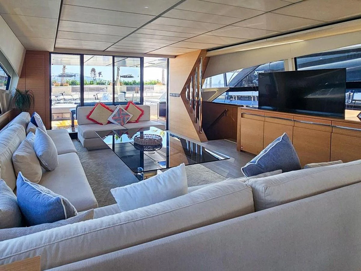 The salon features a spacious seating area with large windows offering ample natural light and a modern entertainment setup. aboard HONEY BADGER Yacht for Sale