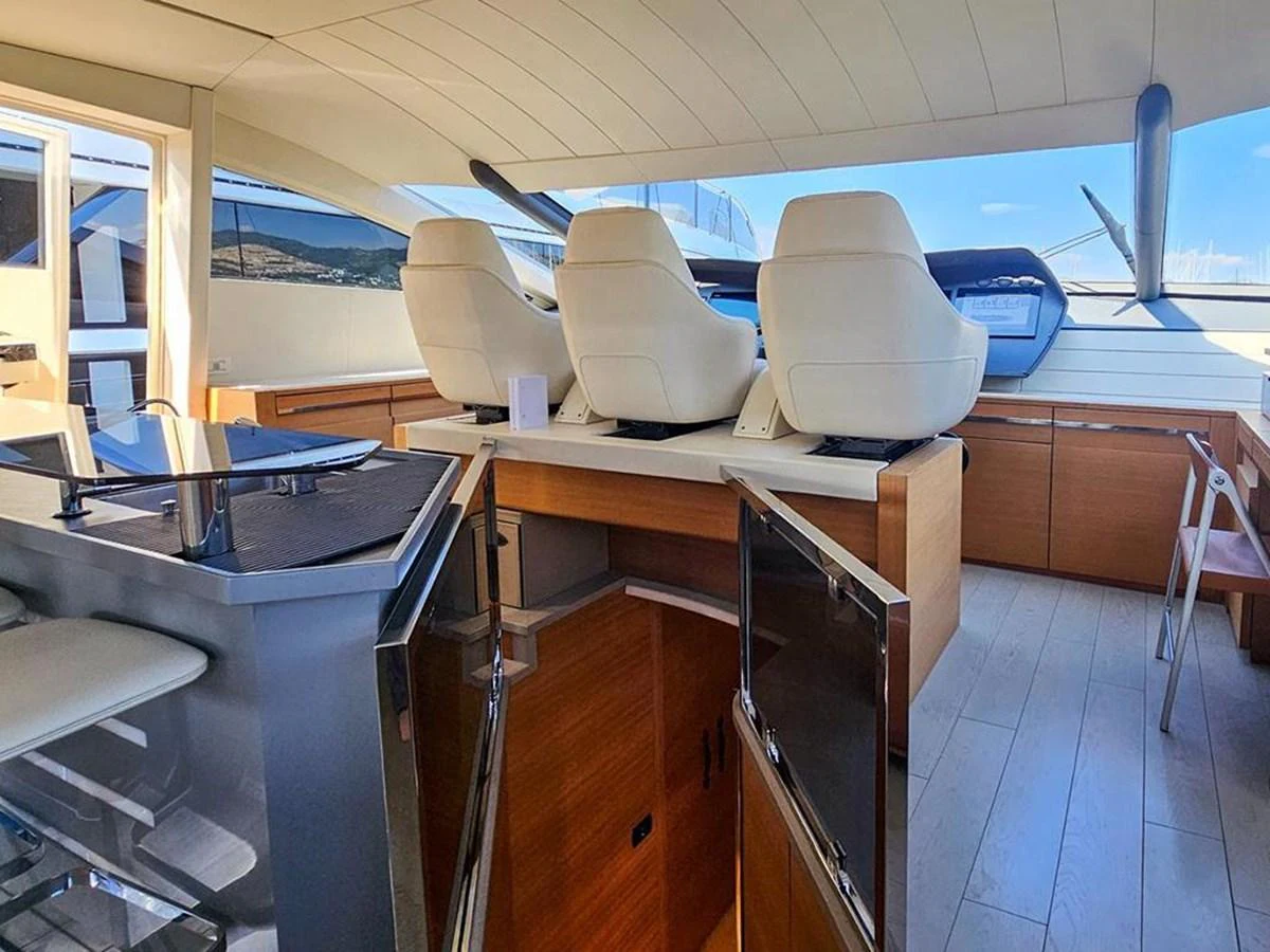 The yacht's helm station features modern seating and a sleek control panel, complemented by a nearby bar area. aboard HONEY BADGER Yacht for Sale