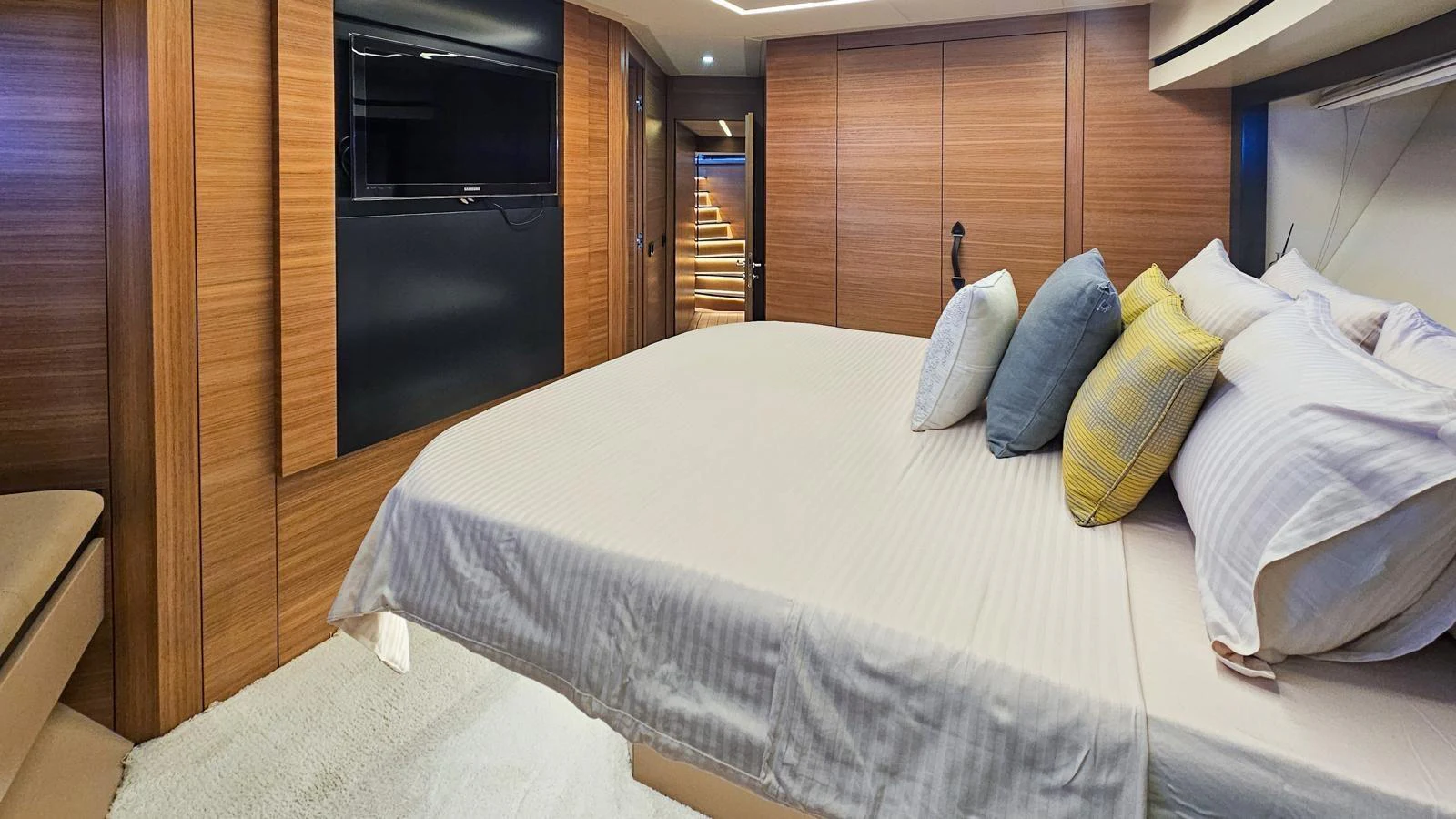 The stateroom features a luxurious bed with plush pillows and modern wooden paneling. aboard HONEY BADGER Yacht for Sale