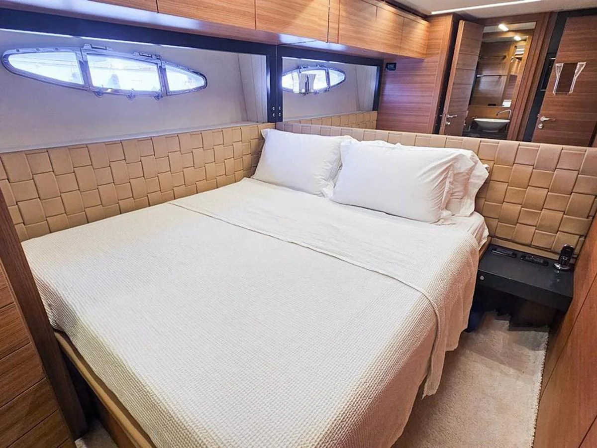A cozy stateroom featuring a large bed with plush pillows and a warm, inviting ambiance. aboard HONEY BADGER Yacht for Sale
