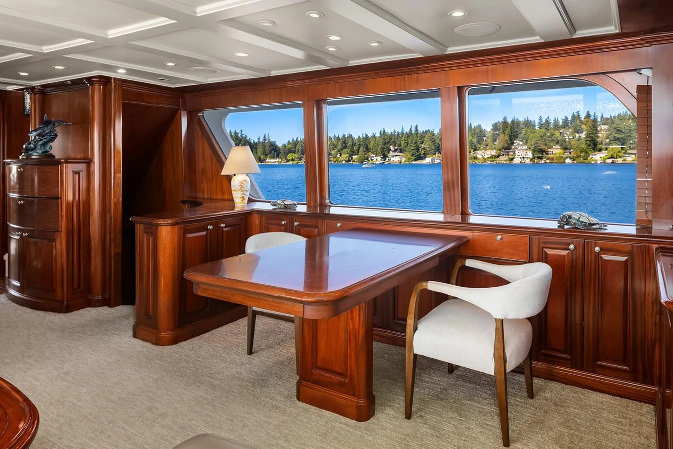 The salon features elegant wood paneling and large windows offering stunning water views. aboard MI AMERE Yacht for Sale