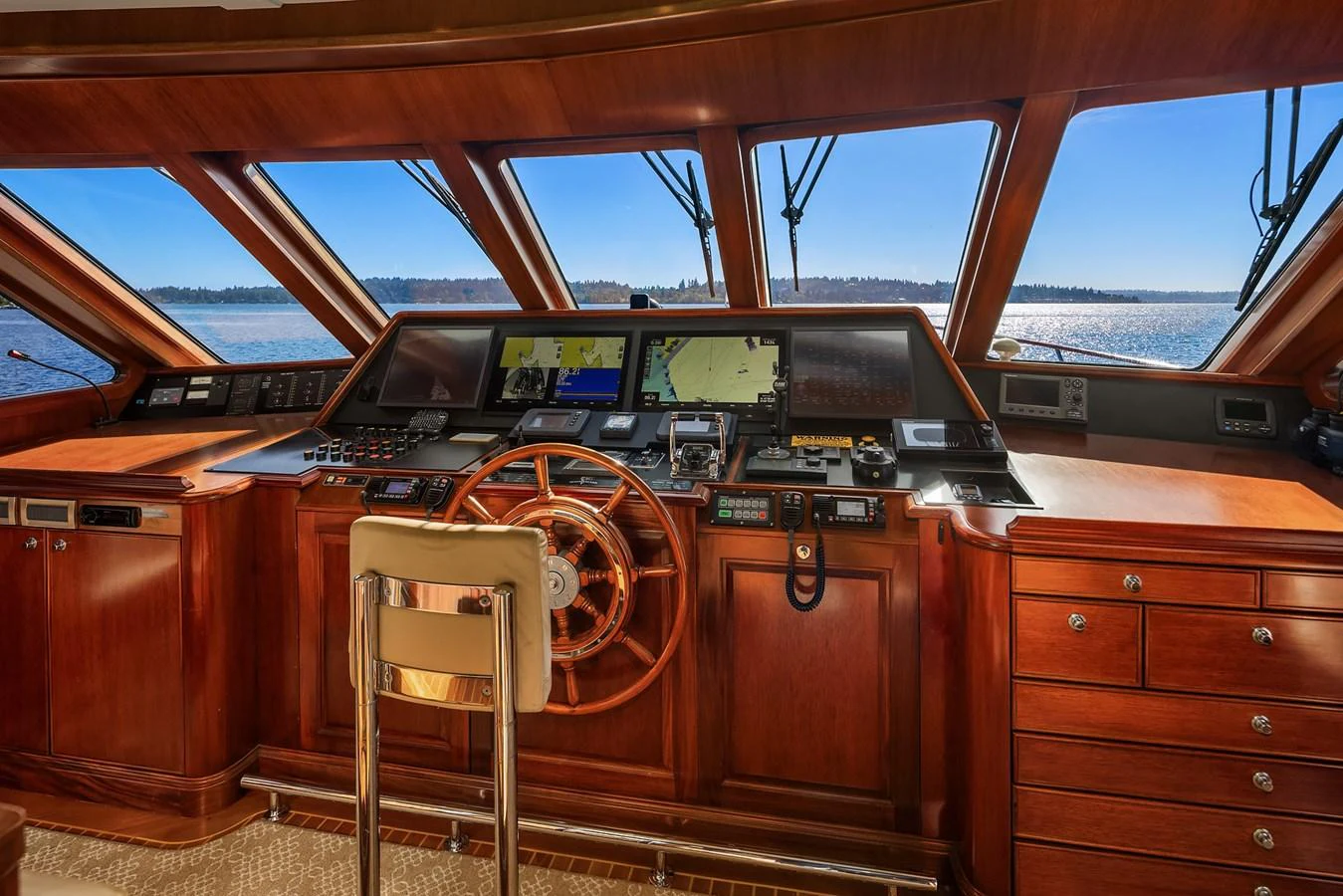 The helm station features rich wood finishes and state-of-the-art navigation equipment, offering a commanding view of the water ahead. aboard MI AMERE Yacht for Sale