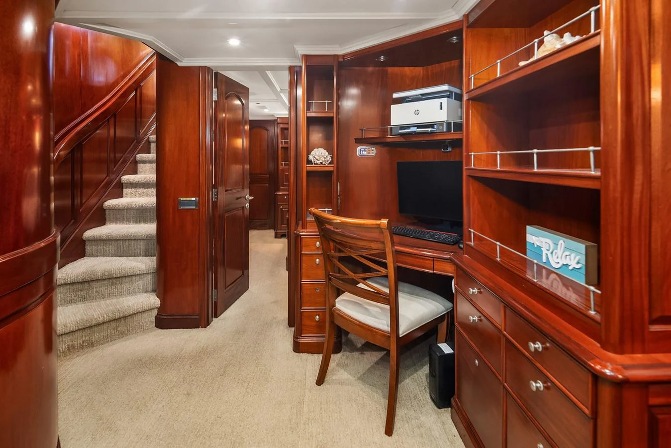 The yacht features a cozy office space with rich wooden cabinetry and a comfortable chair. aboard MI AMERE Yacht for Sale
