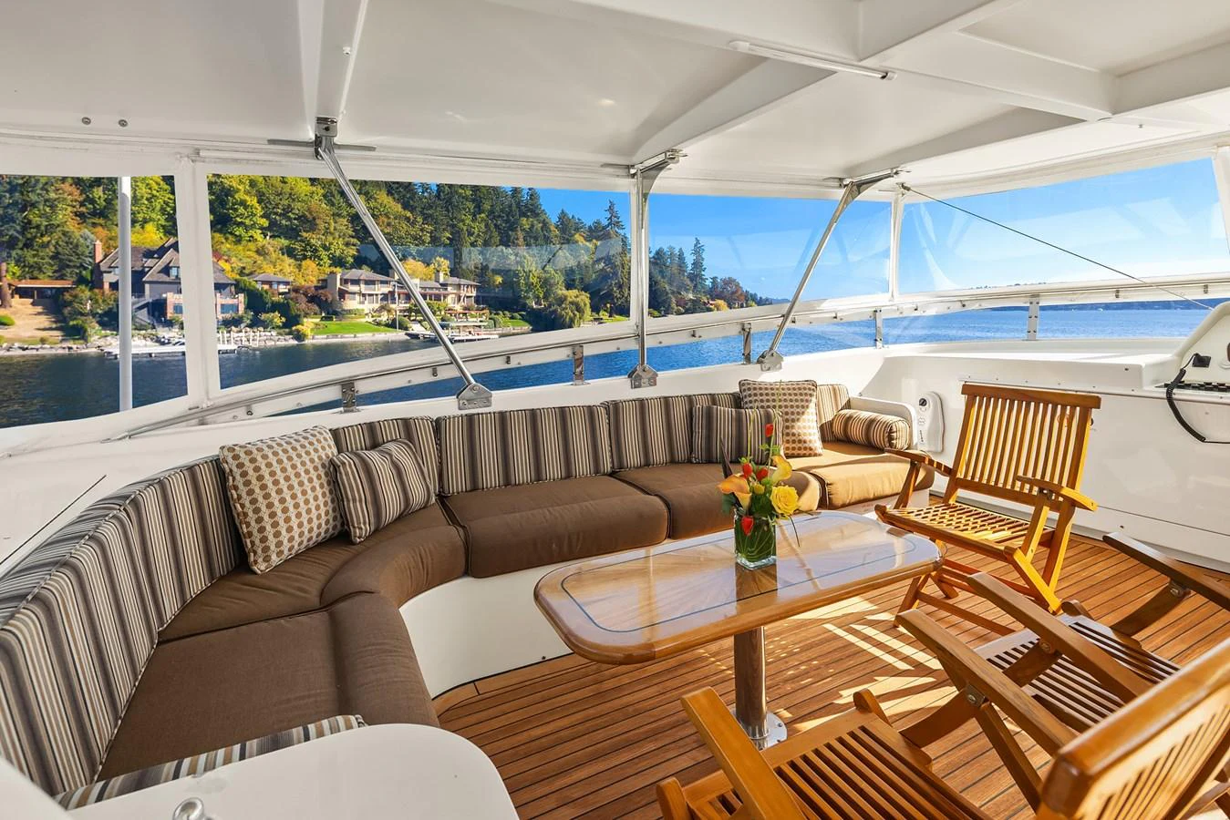 The aft deck features a cozy seating area with a wooden table and chairs, offering a perfect spot to enjoy the scenic views. aboard MI AMERE Yacht for Sale