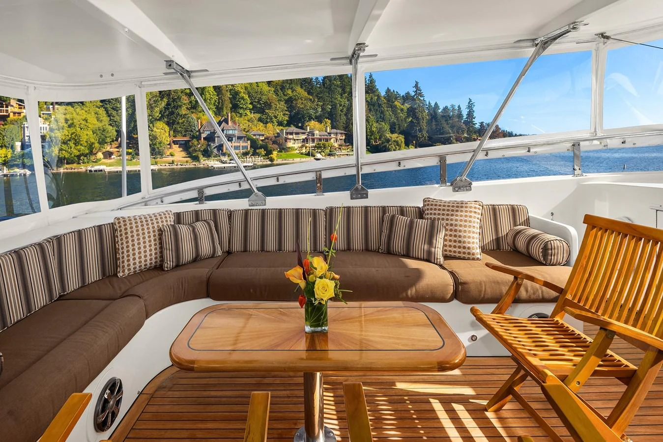 The aft deck features a comfortable seating area with a wooden table and chairs, perfect for enjoying the scenic views. aboard MI AMERE Yacht for Sale