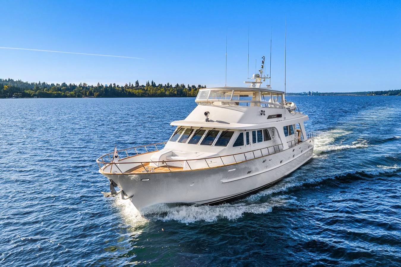A sleek white yacht cruises through calm blue waters under a clear sky. aboard MI AMERE Yacht for Sale