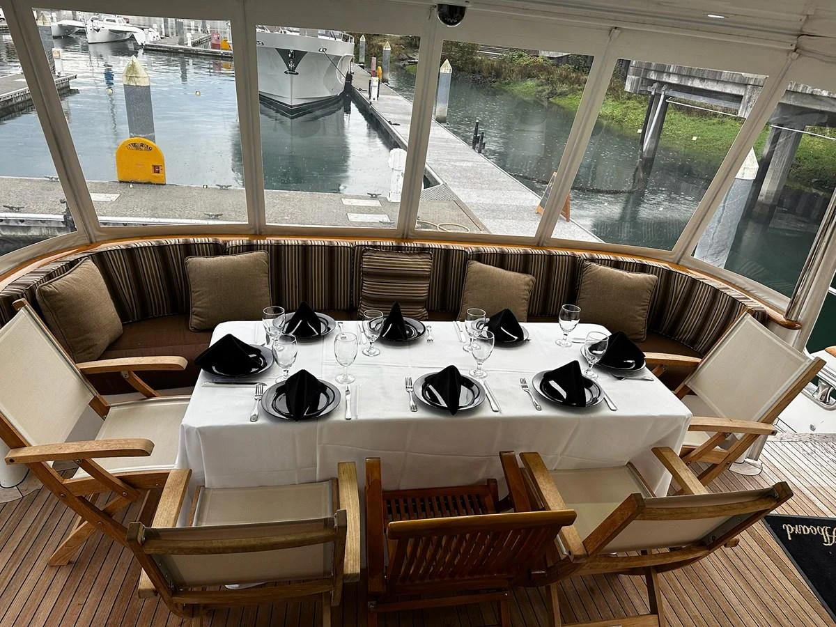 The yacht's dining area is elegantly set for a meal with a view of the marina. aboard MI AMERE Yacht for Sale