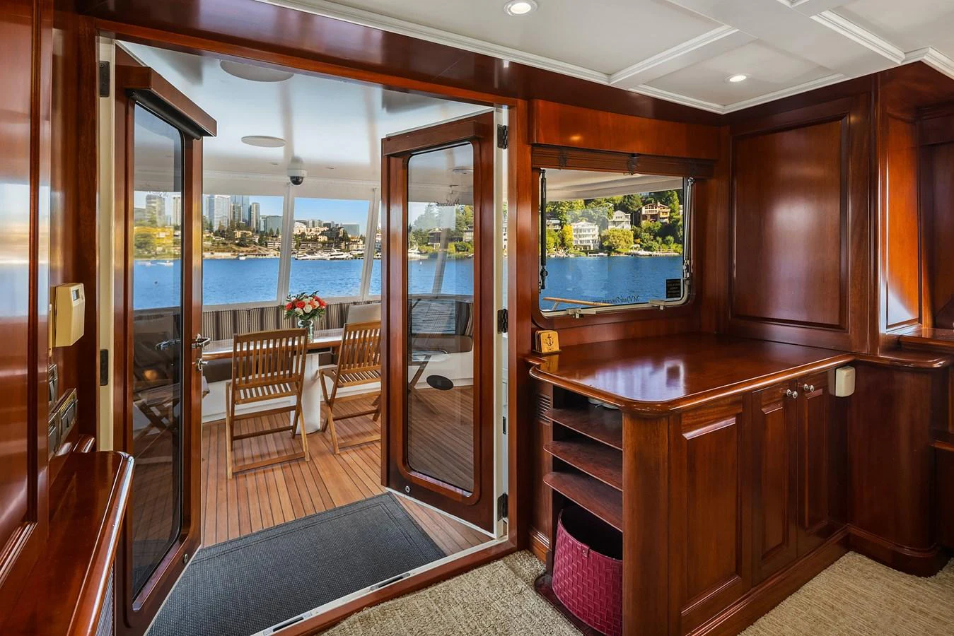 The salon features rich wooden cabinetry and opens to a spacious aft deck with a stunning waterfront view. aboard MI AMERE Yacht for Sale