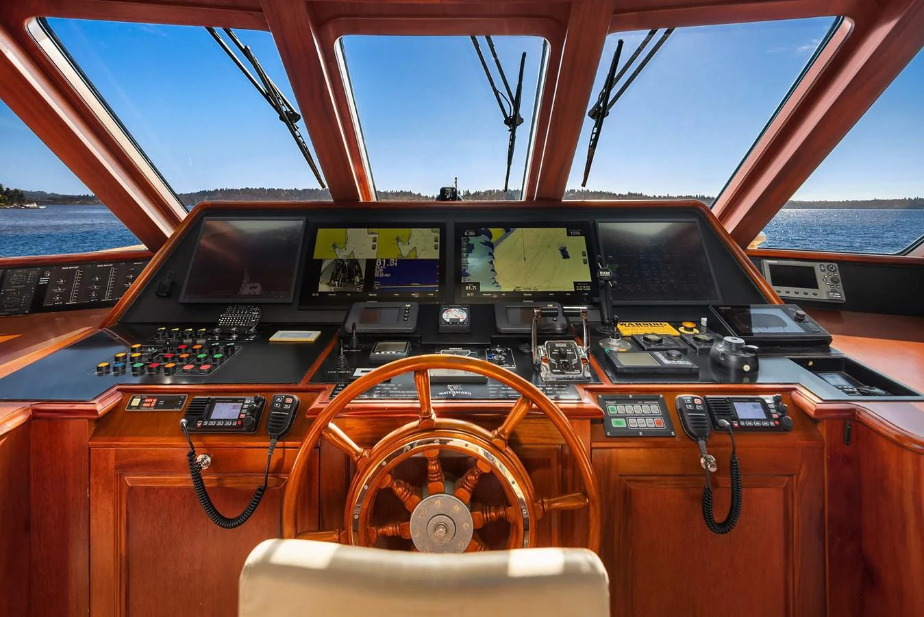 The helm station features advanced navigation equipment and a classic wooden steering wheel, offering a commanding view of the sea. aboard MI AMERE Yacht for Sale