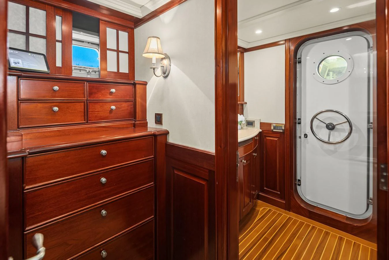 The yacht's interior features rich wooden cabinetry and a nautical-themed door with a porthole. aboard MI AMERE Yacht for Sale