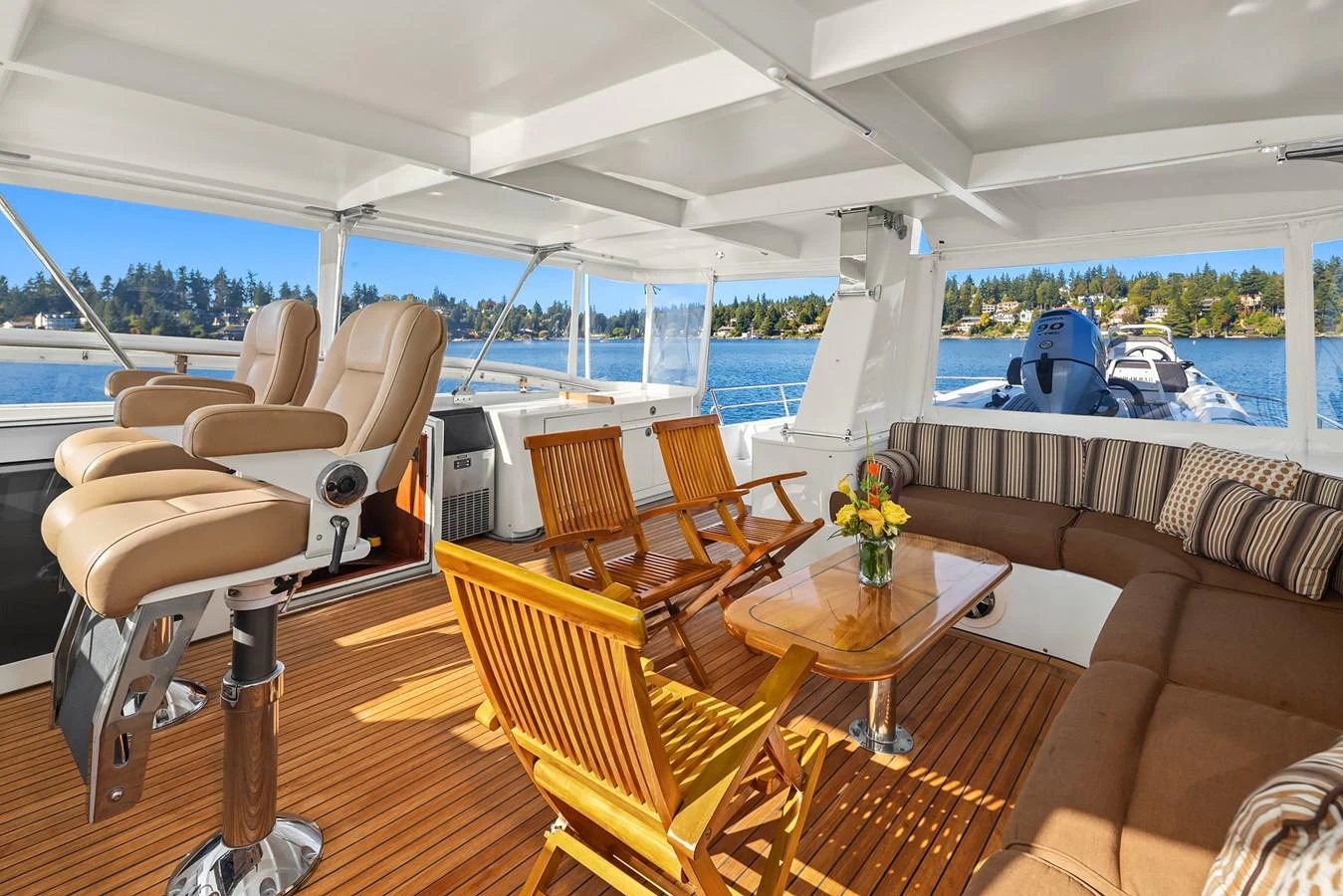 The aft deck features comfortable seating, a wooden table, and a beautiful view of the water. aboard MI AMERE Yacht for Sale