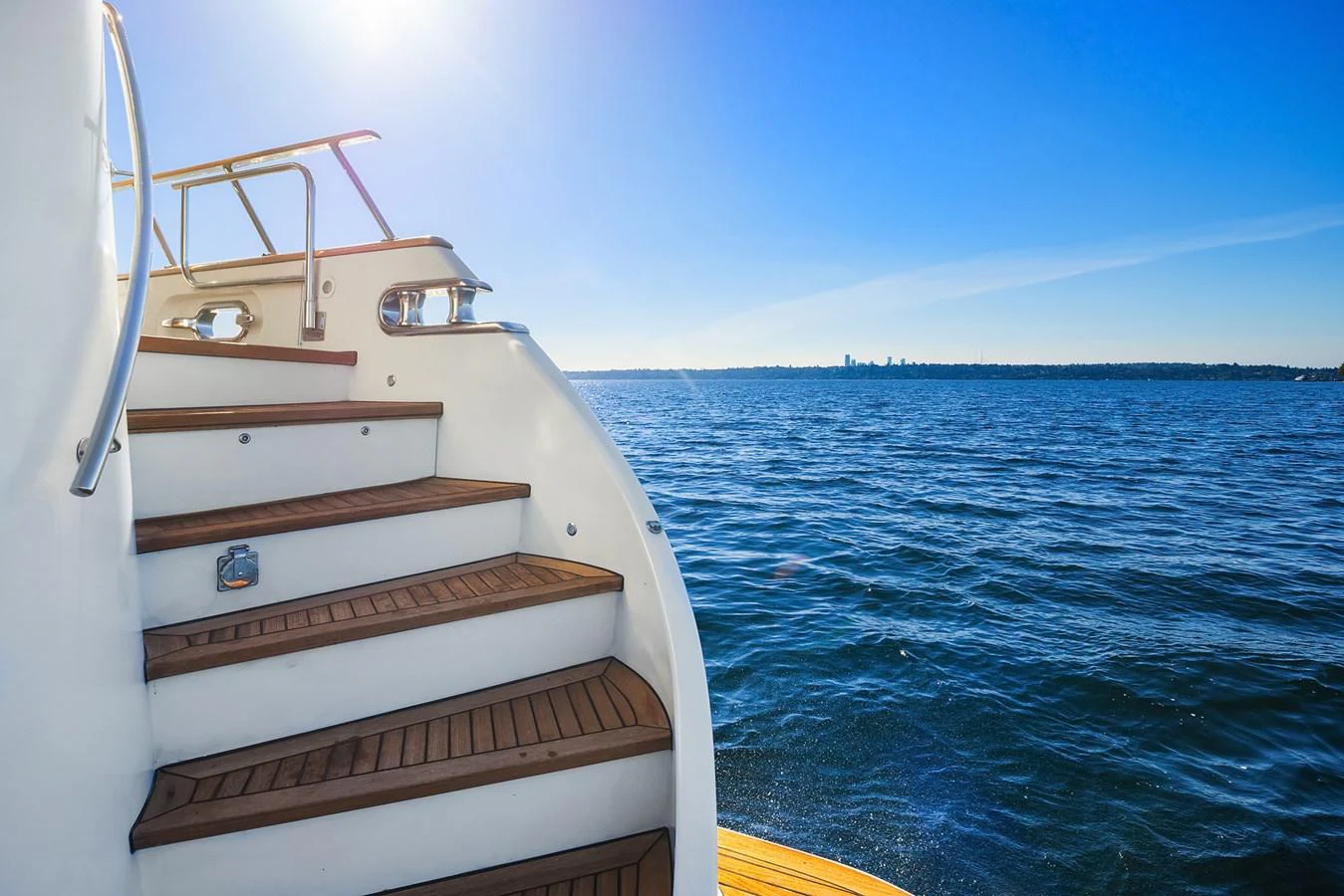A view of the yacht's staircase leading up from the deck, with a scenic ocean backdrop. aboard MI AMERE Yacht for Sale