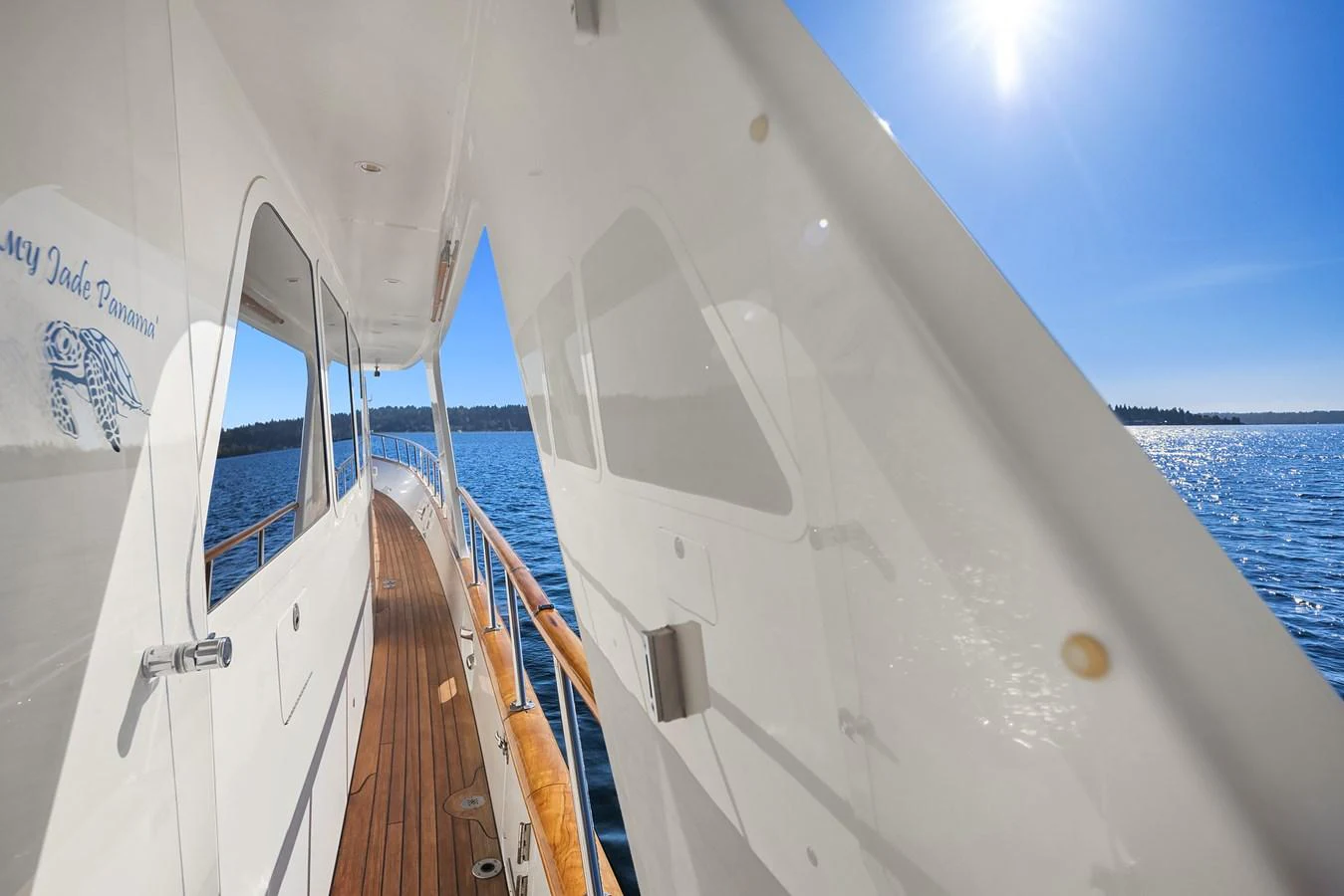 The yacht's side deck offers a serene view of the water under a bright, clear sky. aboard MI AMERE Yacht for Sale