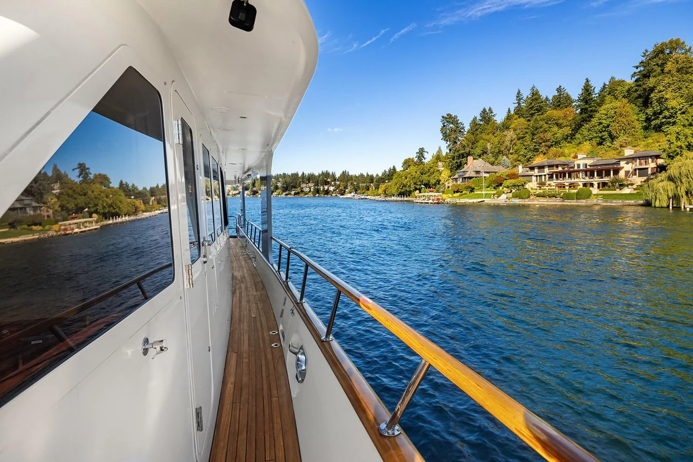 The yacht's side deck offers a serene view of the water and nearby shoreline. aboard MI AMERE Yacht for Sale