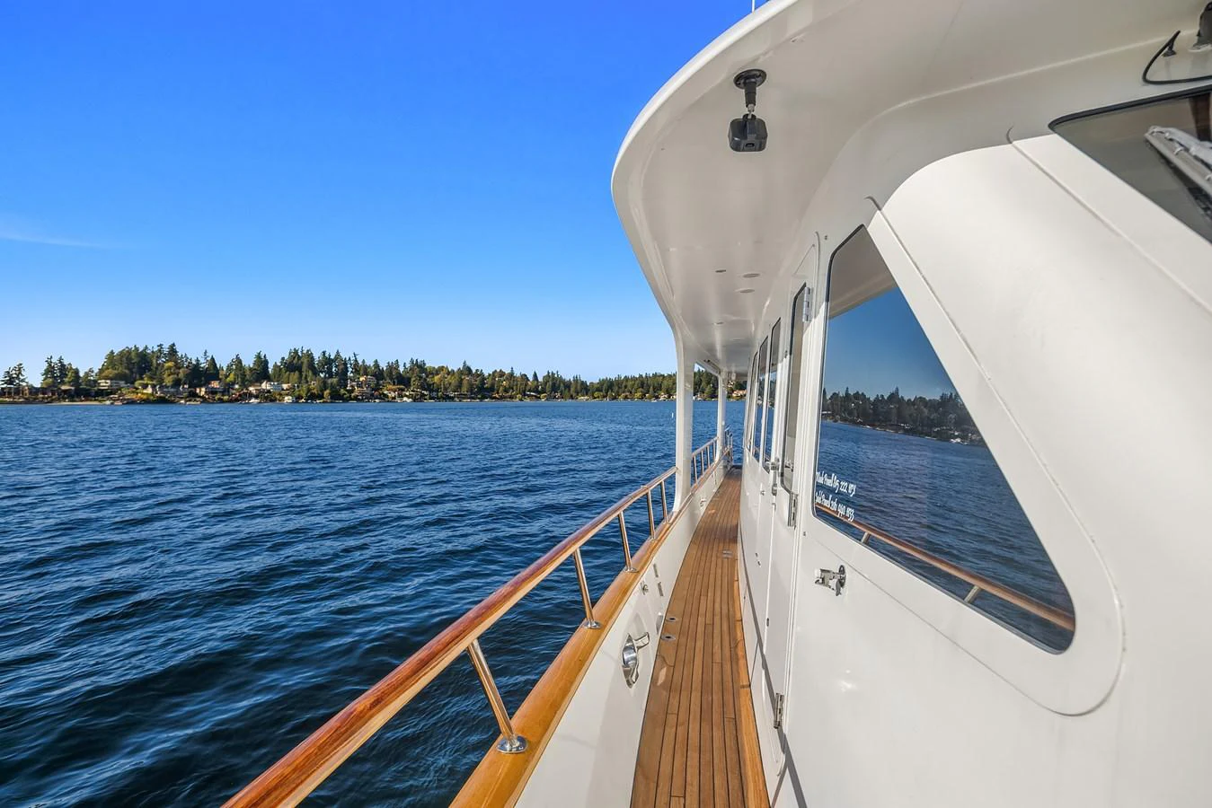 The yacht's side deck offers a serene view of the water and distant shoreline. aboard MI AMERE Yacht for Sale