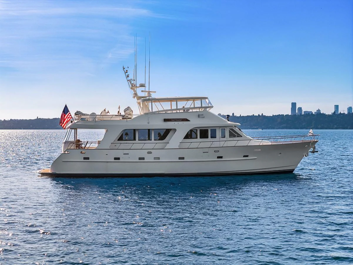 A stunning yacht cruises gracefully on calm waters with a city skyline in the background. aboard MI AMERE Yacht for Sale