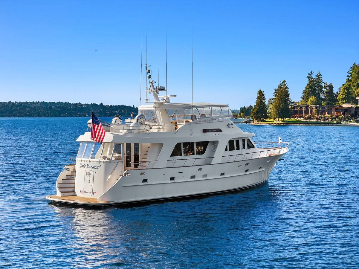 A pristine yacht cruises on calm waters with a scenic shoreline in the background. aboard MI AMERE Yacht for Sale