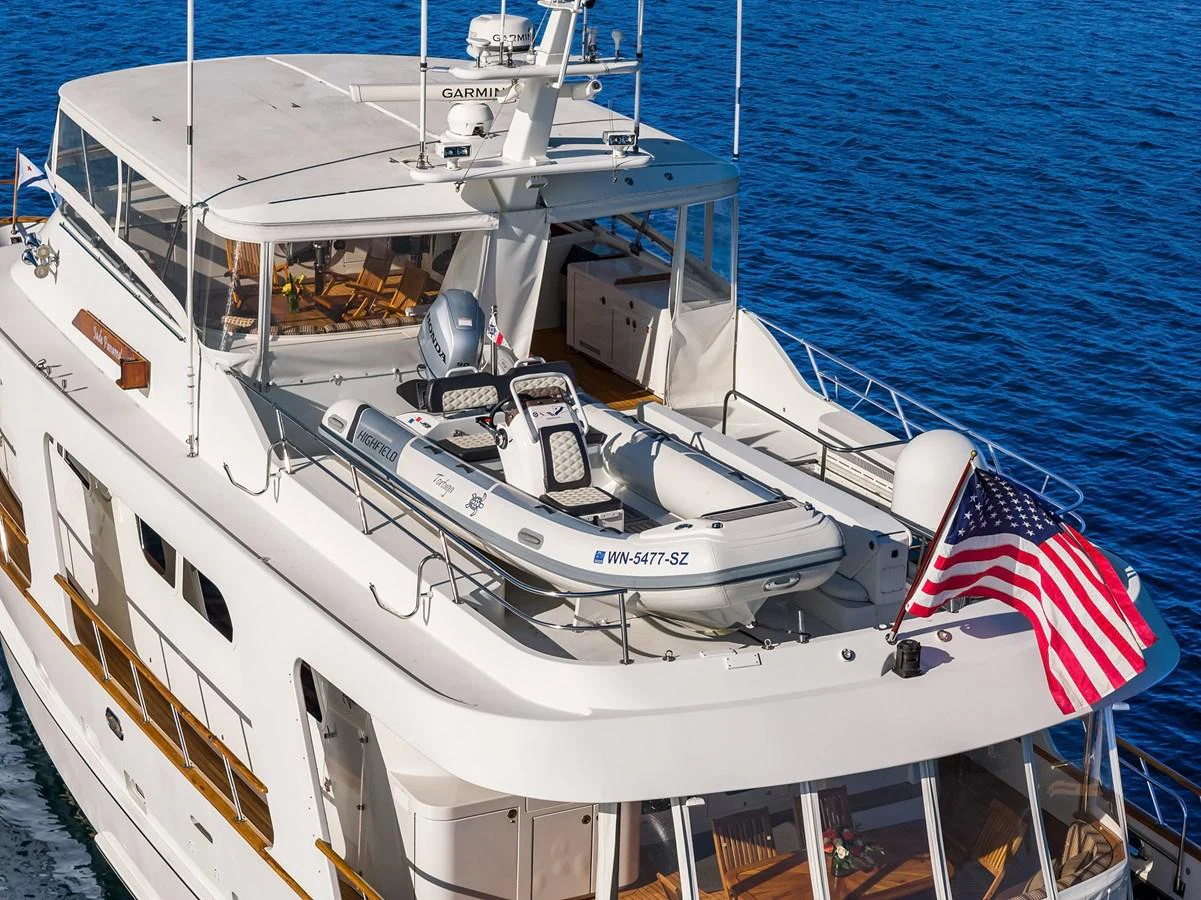 The yacht's upper deck features a tender and an American flag, showcasing its readiness for adventure. aboard MI AMERE Yacht for Sale