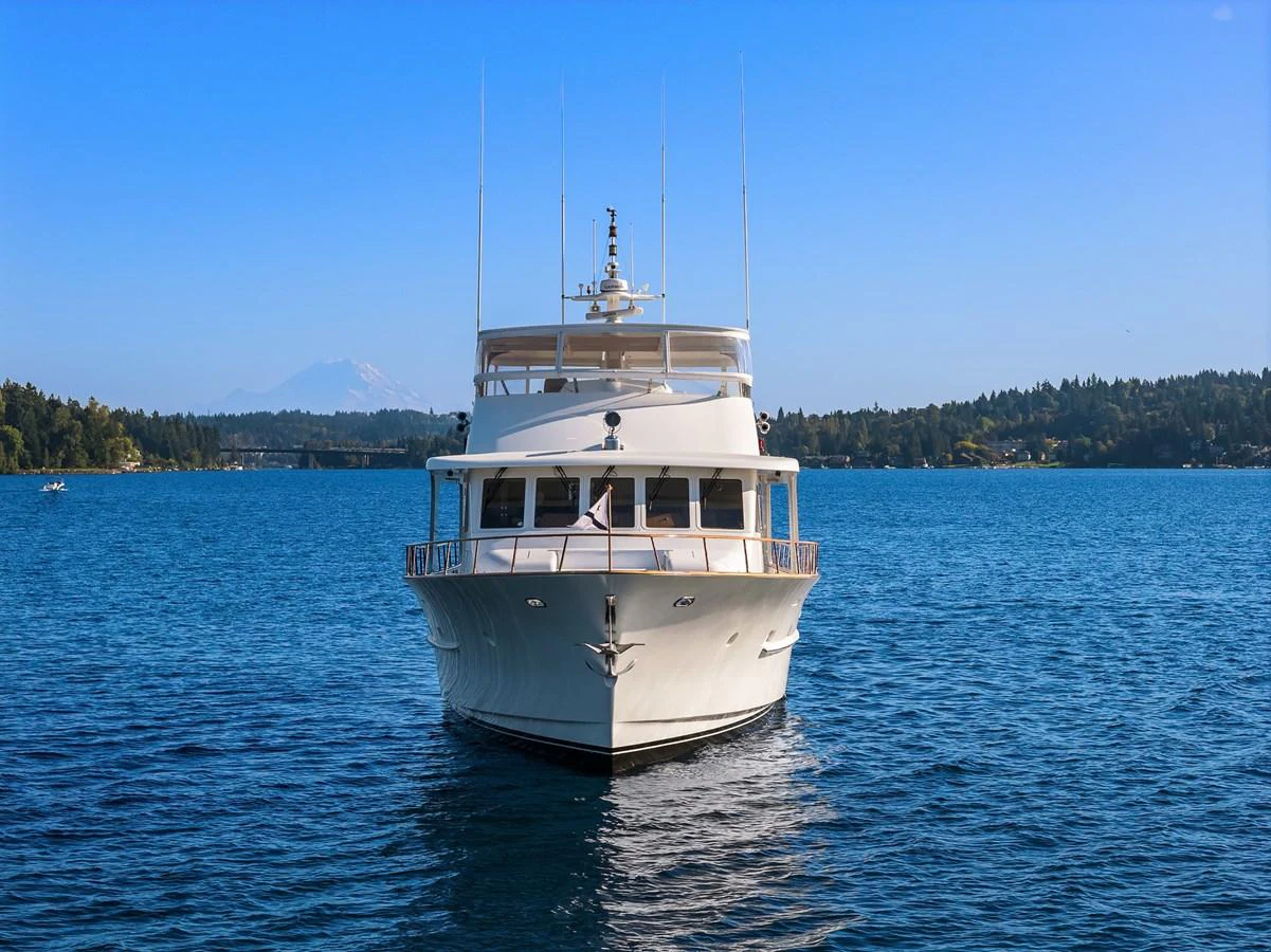 A luxurious yacht is seen head-on, cruising through serene blue waters with a scenic backdrop. aboard MI AMERE Yacht for Sale