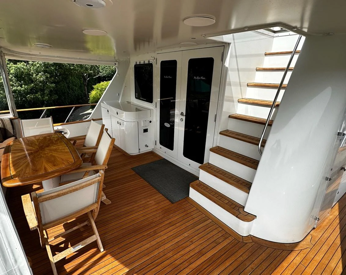 The aft deck features a stylish dining area with wooden flooring and comfortable seating. aboard MI AMERE Yacht for Sale