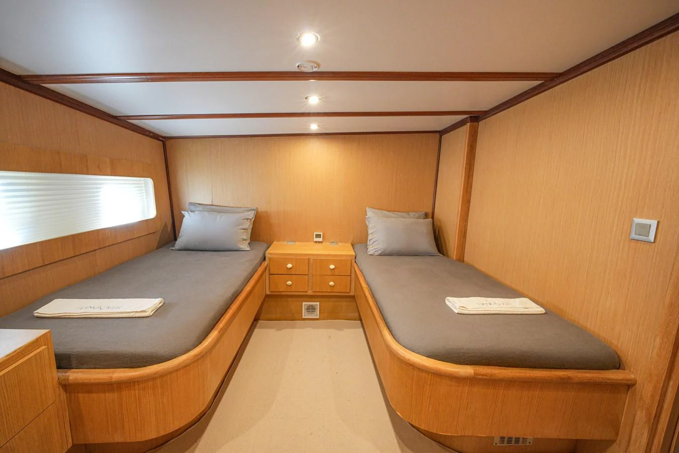 The twin stateroom features two single beds with a warm wood finish and modern lighting. aboard HANGOVER Yacht for Sale