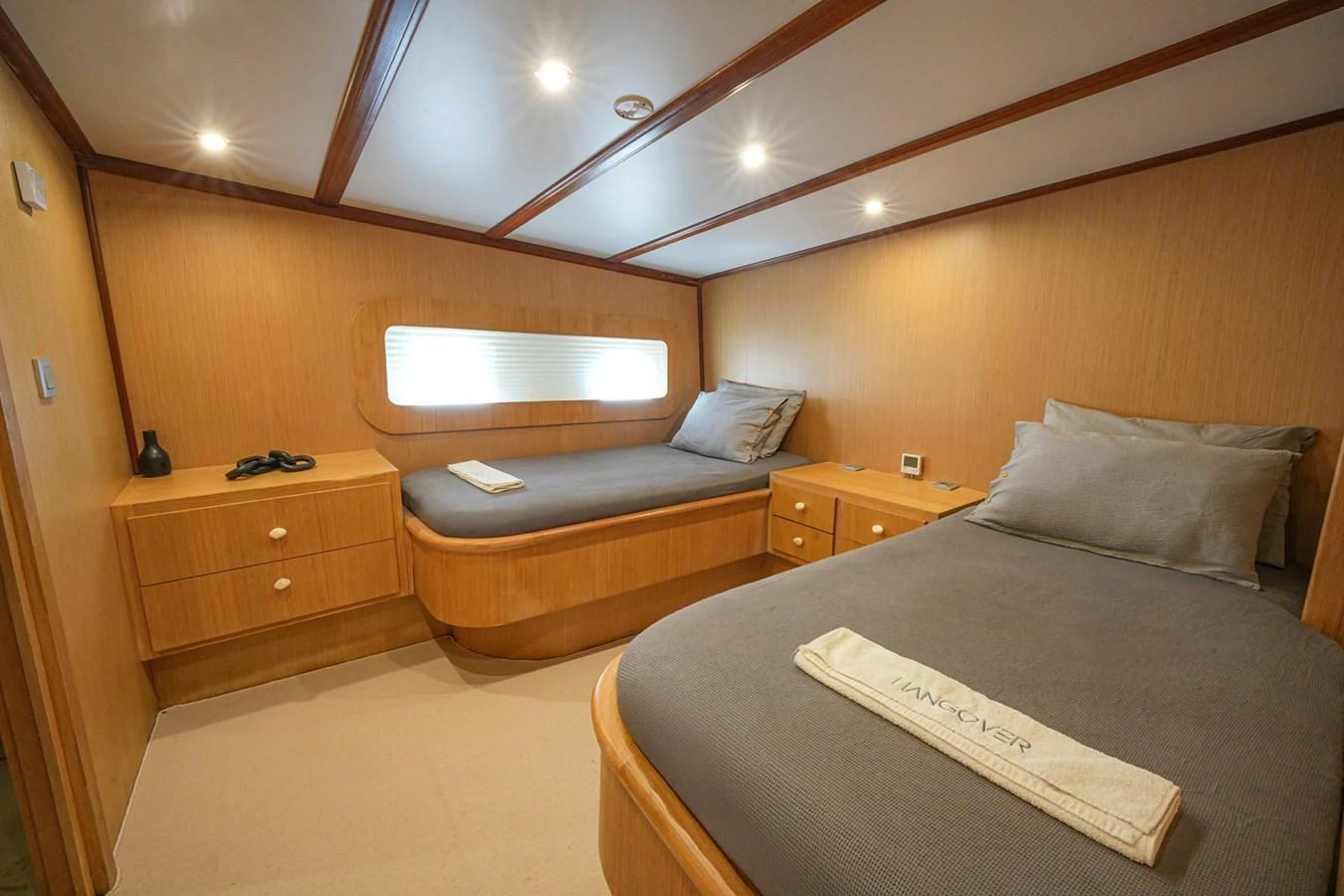 The twin stateroom features two single beds with a warm wood finish and soft lighting. aboard HANGOVER Yacht for Sale