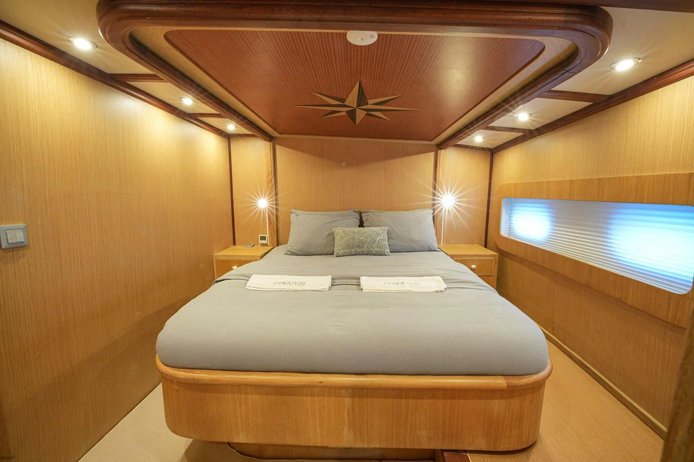 The master stateroom features a luxurious bed with elegant wood paneling and ambient lighting. aboard HANGOVER Yacht for Sale