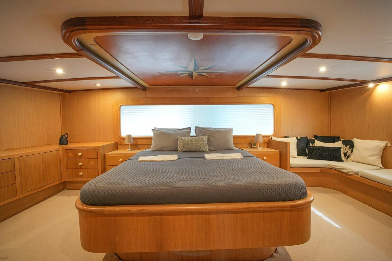 The master stateroom features a spacious bed with elegant wood paneling and ample natural light. aboard HANGOVER Yacht for Sale