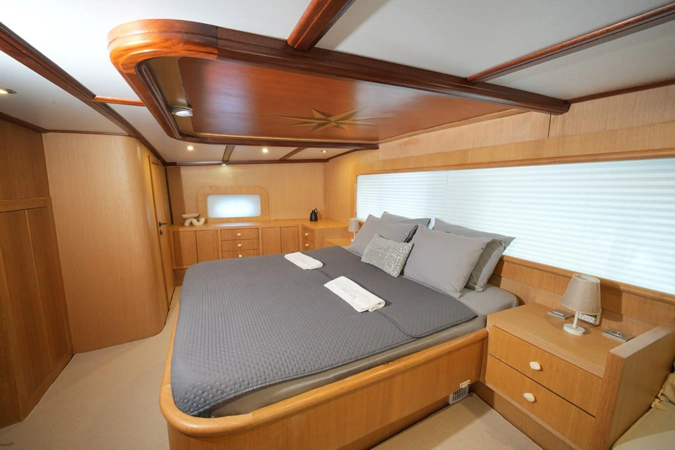 The master stateroom features a spacious bed with elegant wood finishes and ample natural light. aboard HANGOVER Yacht for Sale