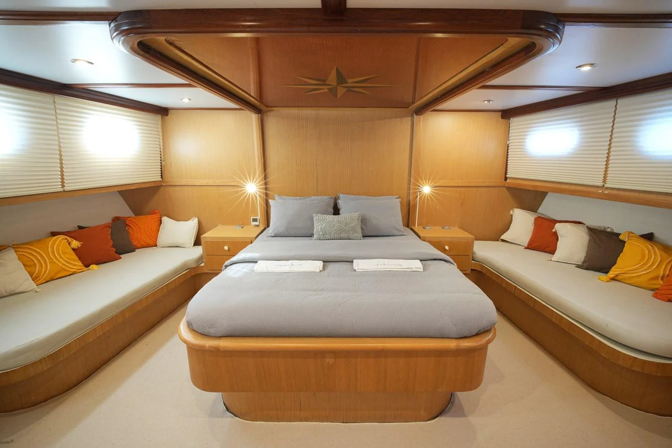 The master stateroom features a spacious bed with elegant wood paneling and ample seating. aboard HANGOVER Yacht for Sale