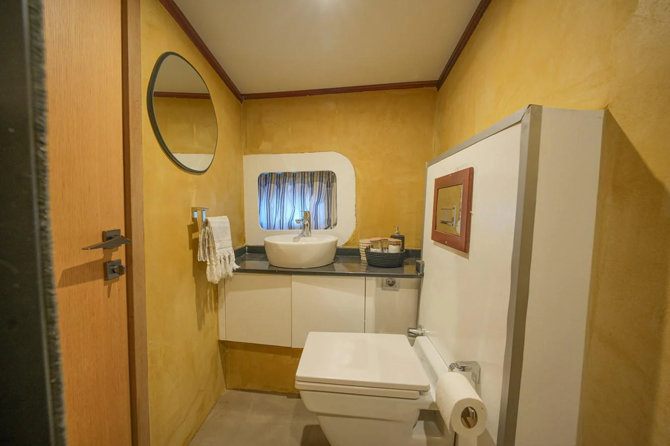 A cozy yacht bathroom with a modern sink and toilet, featuring warm yellow walls and a small window. aboard HANGOVER Yacht for Sale