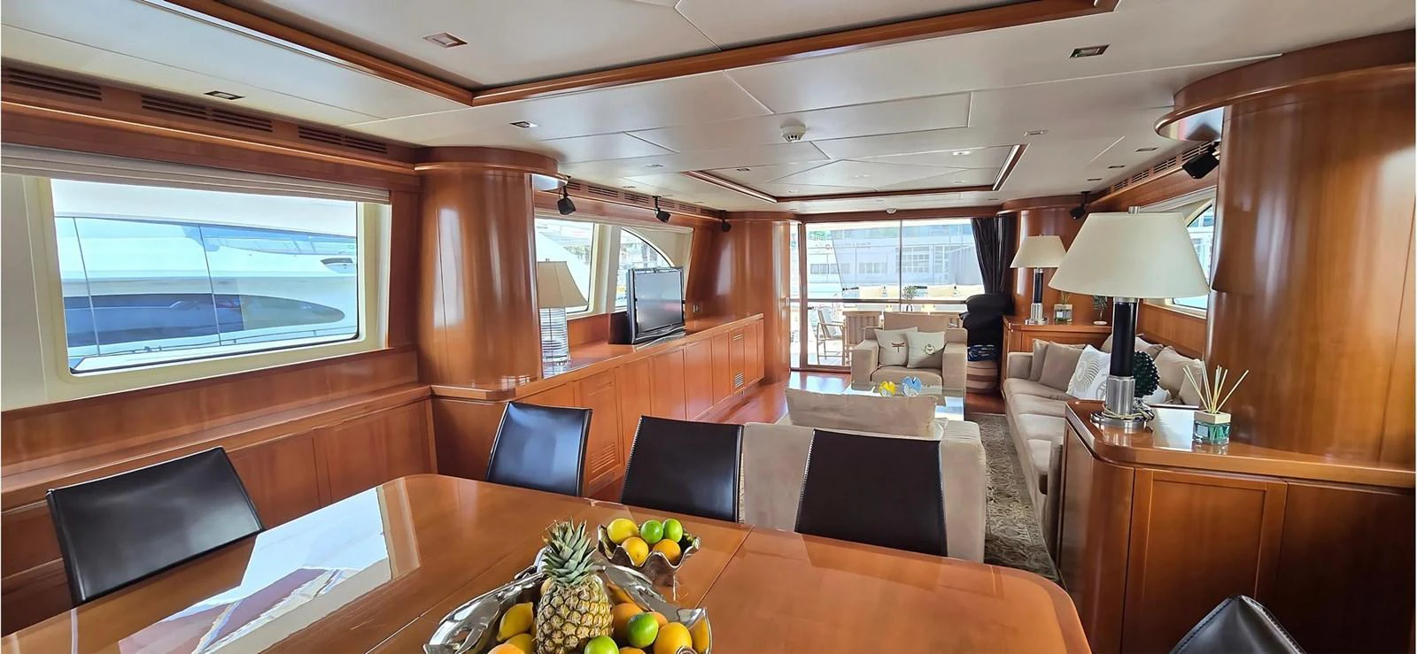 The yacht's salon features elegant wood paneling, a dining area, and a comfortable seating area with large windows for natural light. aboard BALKAN Yacht for Sale