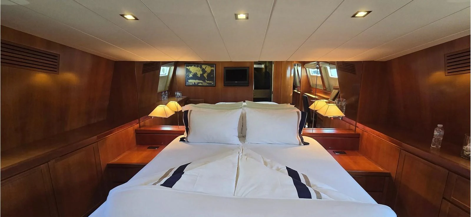 The master stateroom features a luxurious bed with elegant bedding and warm wooden finishes. aboard BALKAN Yacht for Sale