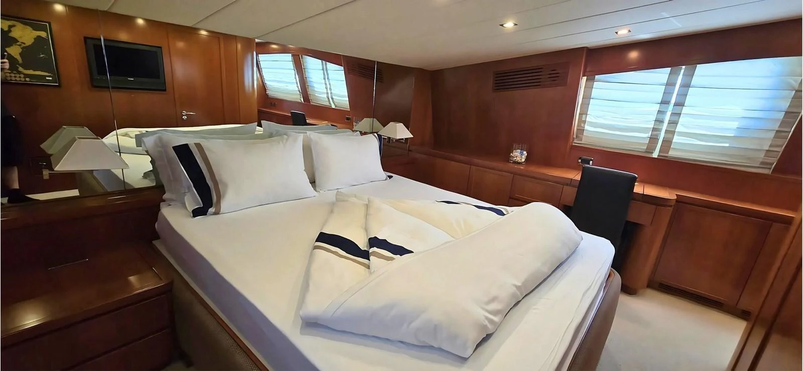 A luxurious stateroom featuring a large bed with plush bedding and elegant wooden finishes. aboard BALKAN Yacht for Sale