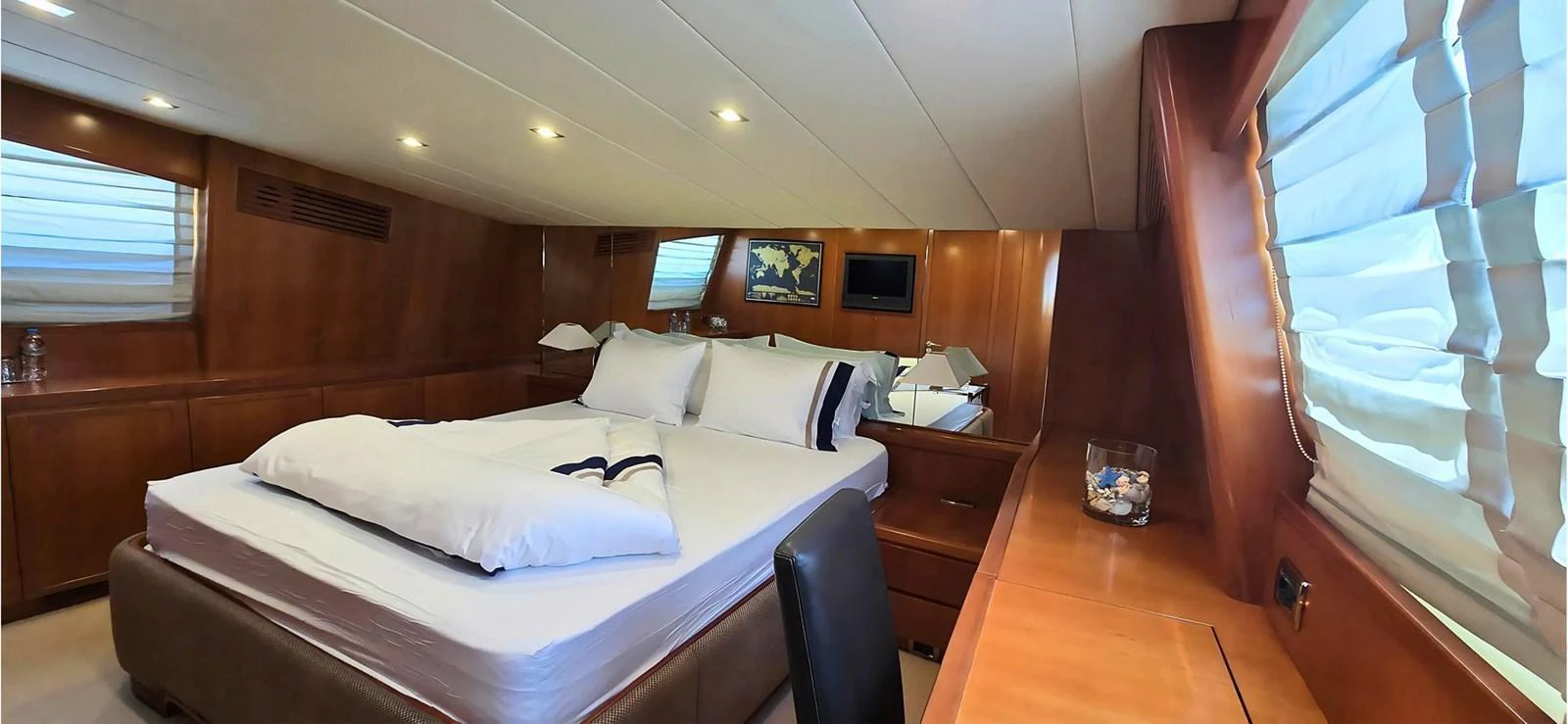 The stateroom features a comfortable bed with elegant wooden paneling and ample natural light. aboard BALKAN Yacht for Sale