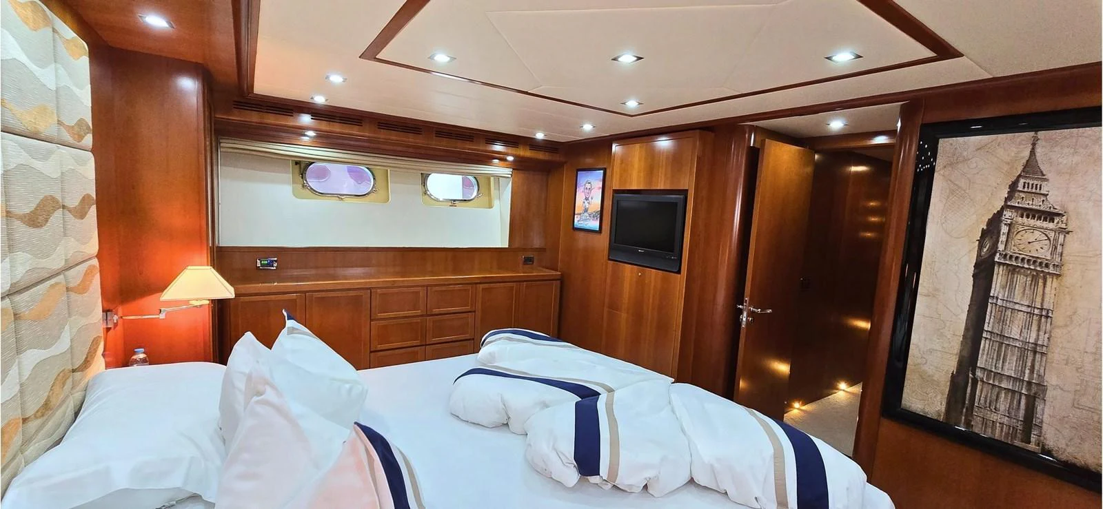 A cozy stateroom featuring a large bed, wooden paneling, and modern amenities. aboard BALKAN Yacht for Sale