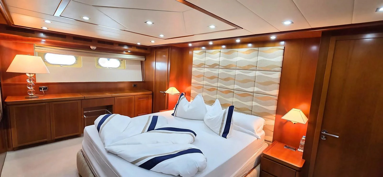 The master stateroom features a luxurious bed with elegant linens and warm wooden accents. aboard BALKAN Yacht for Sale