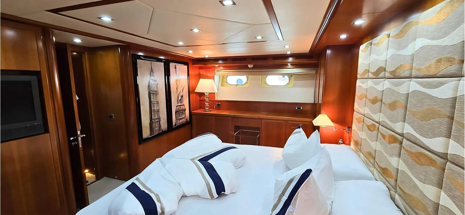 The stateroom features a cozy bed with elegant bedding and warm wooden finishes. aboard BALKAN Yacht for Sale