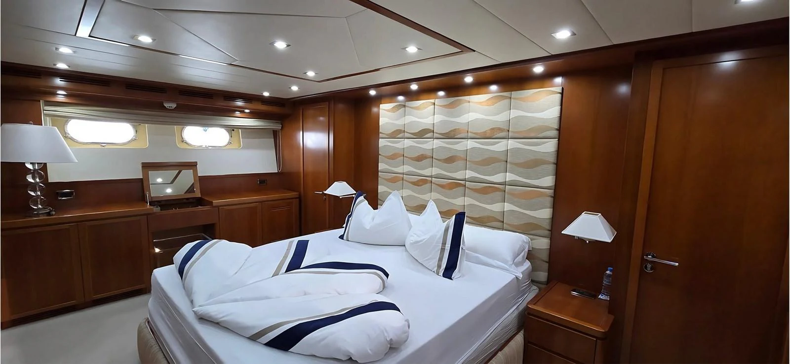 The master stateroom features a luxurious bed with elegant bedding and ample wooden cabinetry. aboard BALKAN Yacht for Sale