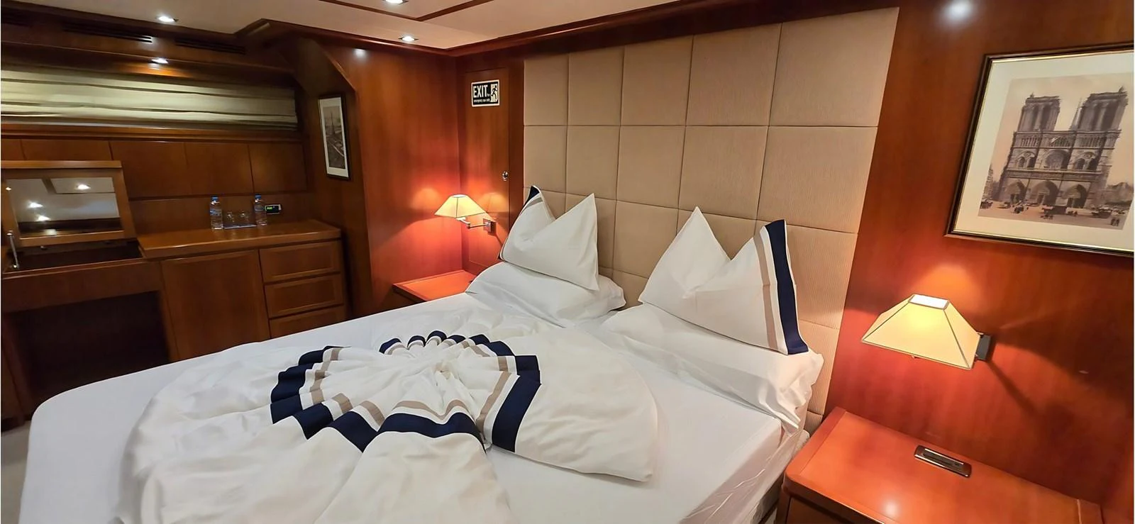 The stateroom features a plush bed with elegant linens and warm wooden accents. aboard BALKAN Yacht for Sale