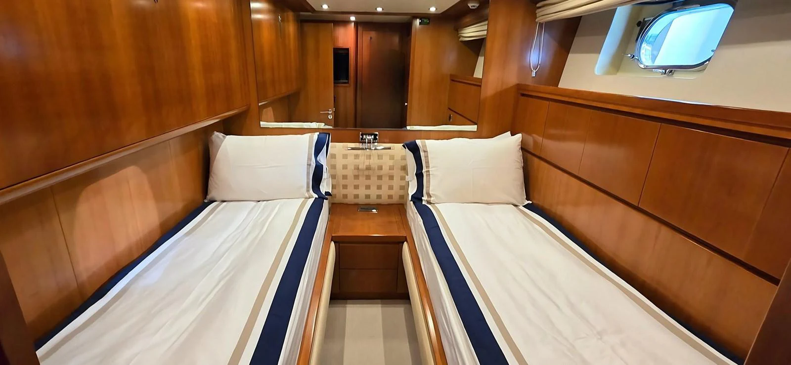 The twin stateroom features two comfortable beds with elegant wood paneling and ample lighting. aboard BALKAN Yacht for Sale