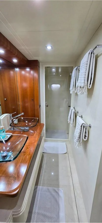 A well-appointed yacht bathroom featuring a glass sink, wooden cabinetry, and a shower area. aboard BALKAN Yacht for Sale