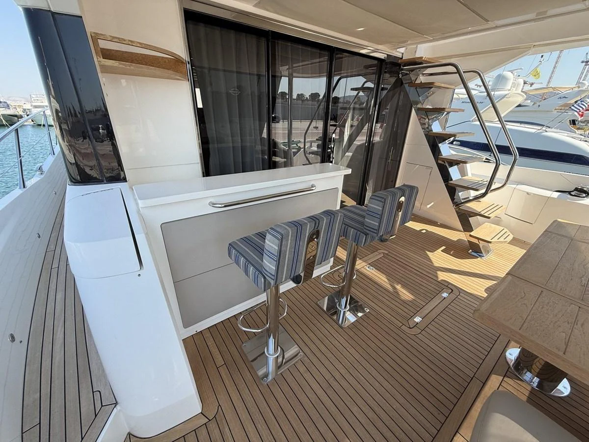 The aft deck features a stylish bar area with modern stools and a staircase leading to the upper deck. aboard "BISHWISH" Yacht for Sale