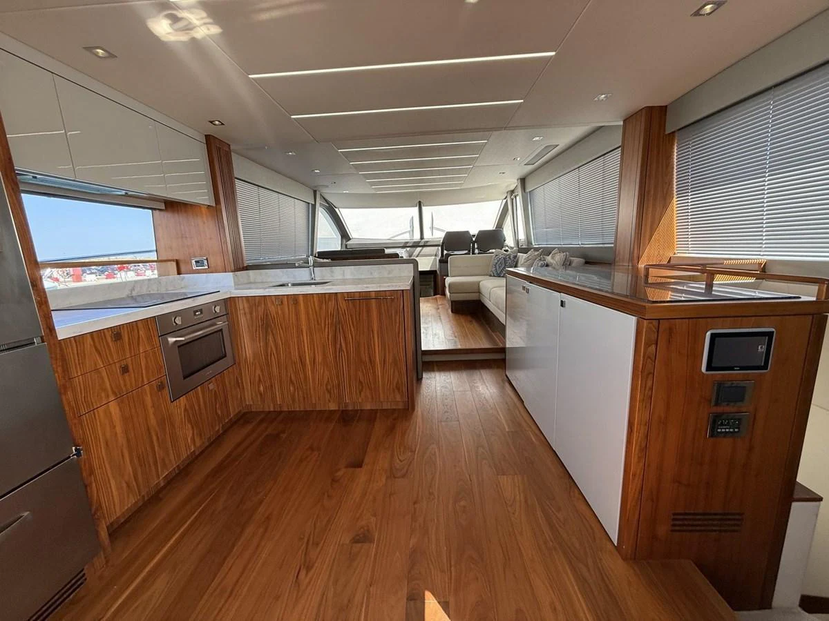 The yacht's galley features modern appliances and elegant wood finishes, leading to a cozy seating area with large windows. aboard "BISHWISH" Yacht for Sale